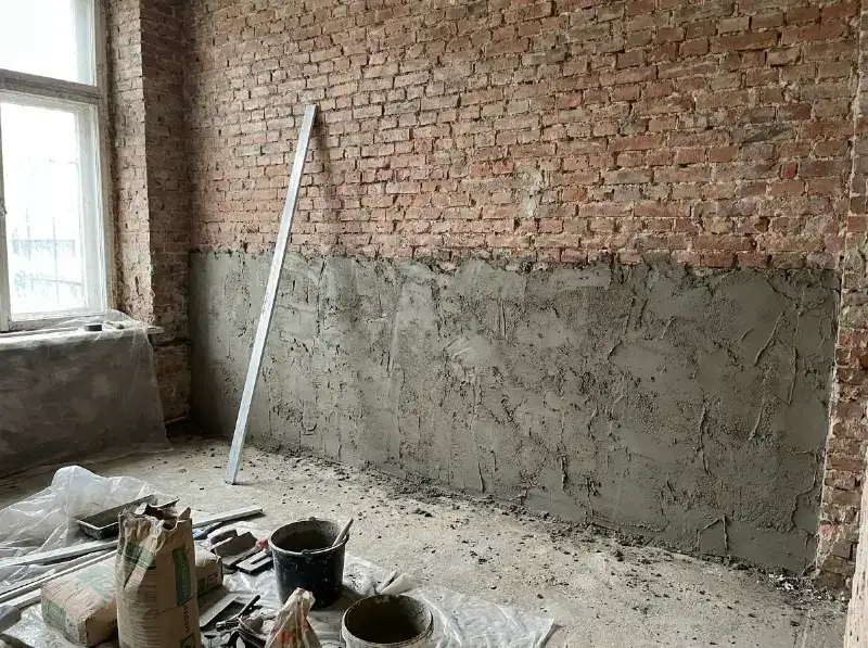 Raaplaag van cementmortel aangebracht op een snelbouwwand, met de rei ernaast